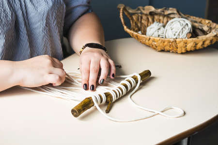 Female hands weave macrame the home workshop. Boho lifestyle. Hobby hobby concept. Selective focus horizontal frame.の写真素材