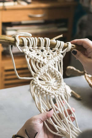 Female hands weave macrame the home workshop. Boho lifestyle. Hobby hobby concept. Selective focus