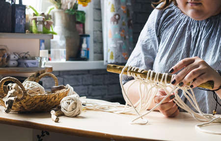 Female hands weave macrame the home workshop. Boho lifestyle. Hobby hobby concept. Selective focus horizontal frame.の写真素材