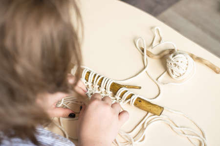 Female hands weave macrame the home workshop. Boho lifestyle. Hobby hobby concept. Selective focus...