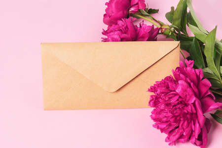 Postal envelope beautiful burgundy peonies. Floral background flat layout. Frame of fresh flowers....