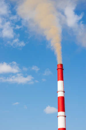 Industrial chimneys smoke smog on blue sky. Air pollution disaster concept. Day of the Planet Earth. Vertical frameの写真素材