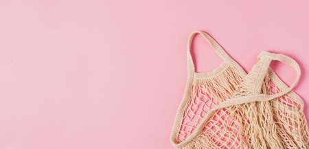 Fashionable braided string bag empty on pink pastel background. Horizontal frame copy space bannerの写真素材