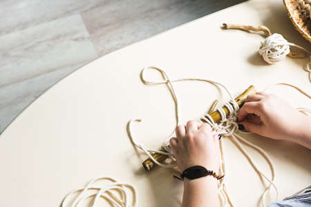Female hands weave macrame in the home workshop. Boho lifestyle. Hobby hobby concept. Selective focus horizontal frame.の写真素材