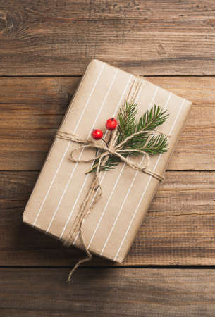 Handmade holiday gift box in paper packaging on a dark wooden background. Zero West concept. Top...