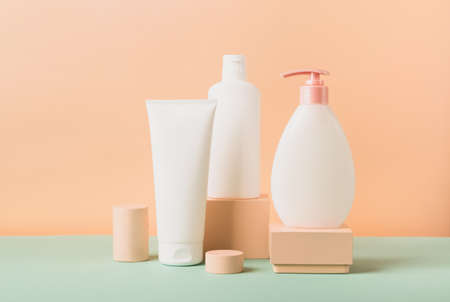 Group of cosmetics in various tubes and bottles on a modern abstract podium on a pastel background. Template for advertising cosmetic products. Front view copy spaceの写真素材