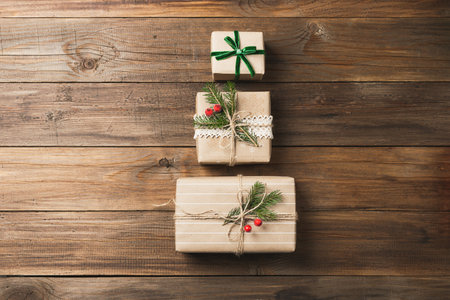 Gift holiday boxes handmade gifts with satin ribbons bows in paper wrapping on a dark wooden background. Zero West concept. Flat top view copy spaceの写真素材