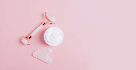 Facial massage set roller scraper gua sha bottle oil serum for face care on pastel pink background. Lifting and toning fitness for the face at homeの写真素材
