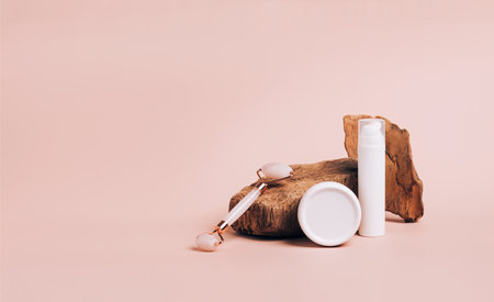 Set of serum oil cosmetic product roller for unconventional massage guache on modern abstract podium pastel pink background. Fashionable podium natural stone material. Copy Horizontal Frame Spaceの写真素材
