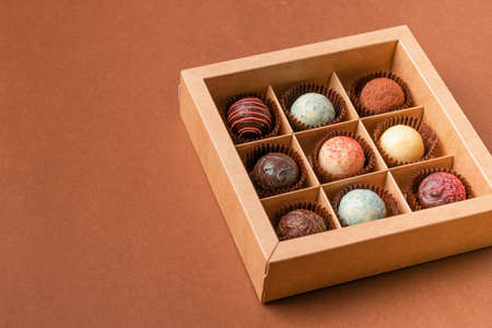 Chocolate candies truffle from various chocolate toppings in a box with a satin ribbon against a...