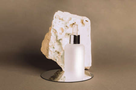 A bottle of gel serum of a cosmetic product on the podium made of natural materials. Natural organic SPA cosmetics. Front view copy spaceの写真素材