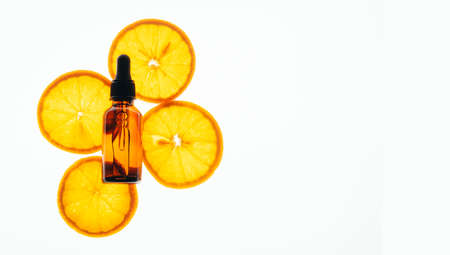 Bottle of cosmetic product oil serum gel made from juicy ripe orange on a white background. Health...