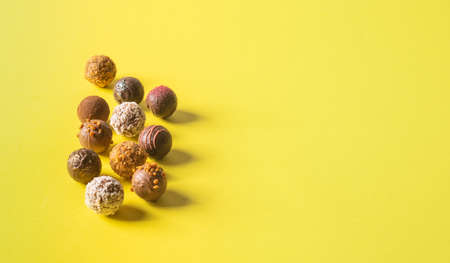 Chocolate truffle candies with various fillings on a bright yellow background. Holiday dessert flat layout copy spaceの写真素材