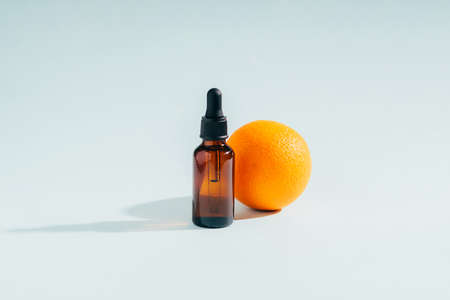 Cosmetic products gel serum oilanti-cellulite remedy from a juicy ripe orange in various bottles on a blue background sunlight hard shadows.の写真素材