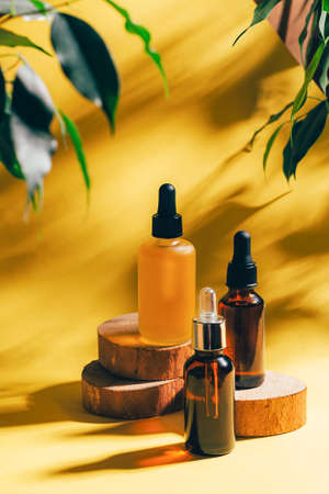 Cosmetics for face body for SPA procedures. Aromatherapy essential oil gel serum on wooden podiums yellow backgroundの写真素材