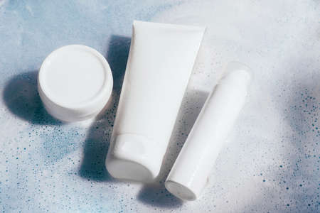 Cosmetics foam gel shampoo bright blue background water with foam bubbles. Cosmetics products for...
