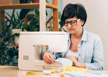 A woman sews homemade medical mask sewing machine during the coronavirus pandemic. DIY virus protection mask preventの写真素材