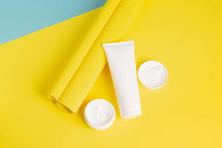 A set of cosmetics in various white packaging on a modern abstract yellow background. Health beauty spa treatmentsの写真素材