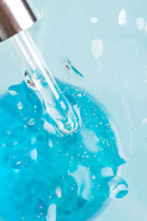 Cosmetic liquid gel serum lubricant hyaluronic acid in a pipette on a blue background. Facial body...