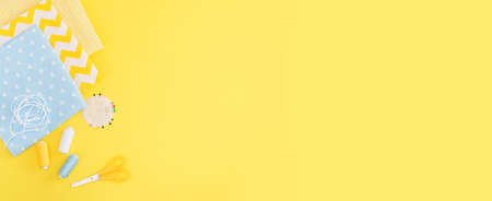 The sewing accessories are yellow background. Tape measure, thread, fabric and sewing needles. The...
