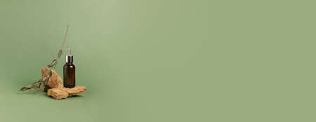 A bottle of serum oil cosmetic on an abstract podium made of natural materials stones plants green...