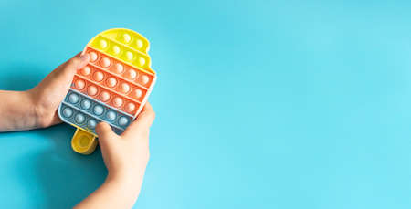 Fashionable touch bright toy antistress in childrens hands blue background copy spaceの写真素材