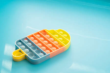 Fashionable touch bright toy antistress  blue background copy space. Silicone toy soft bubbles to...