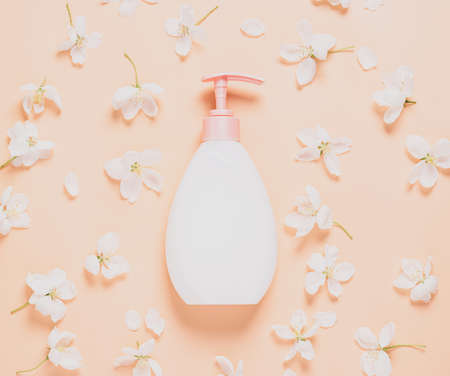 Cosmetic bottle of liquid soap cream for moisturizing and caring for body and face against a background of fresh flowersの写真素材