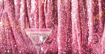 Martini cocktail background pink shiny curtain. Alcoholic classic drink with ice in elegant glass for the celebrationの写真素材