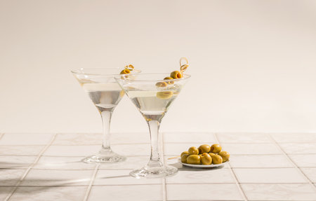 Martini cocktail with olives on the tiled table. An alcoholic classic drink with ice in an elegant glassの写真素材