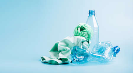 Empty plastic bottle and various fabrics made of recycled polyester fiber synthetic fabric on a blue backgroundの写真素材