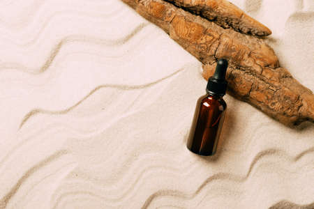 Serum cosmetic bottle on sand background. Abstract podium natural materials product presentation sandy background.の写真素材