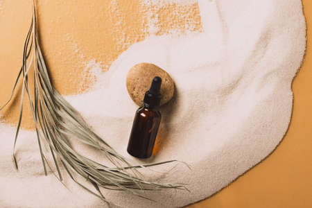 Serum cosmetic bottle on sand background. Abstract podium natural materials product presentation sandy background.の写真素材