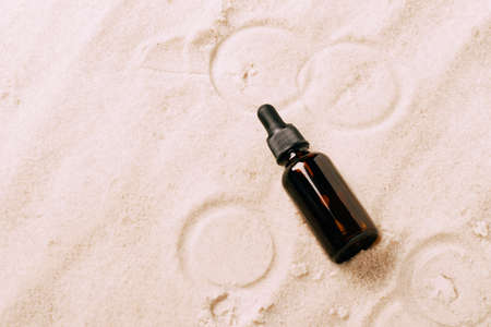 Bottle of serum oil cosmetic product beach sand background. Abstract podium product presentation on a sandy backgroundの写真素材