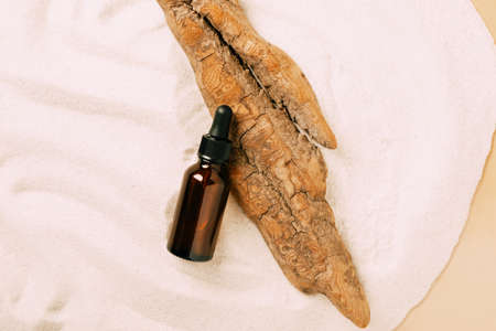Bottle of cosmetic product serum oil dry tree podium beach white sand. Abstract podium product presentation sandy backgroundの写真素材
