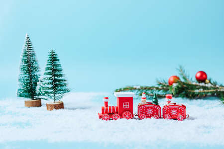 Christmas toy steam train with fir tree, snowman, gifts on a snowy winter background with snow garland and sparkles. Mock up holiday card Christmas or New Year copy space.の写真素材