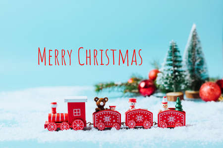 Christmas toy steam train with fir tree, snowman, gifts on a snowy winter background with snow...