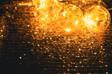 Festive Christmas garland of golden light bulbs shiny background with sequins and sparkles. Party celebration conceptの写真素材