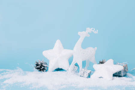 Christmas toy white deer star blue background, snow sparkles, confetti. Christmas or New Year card place for text.の写真素材