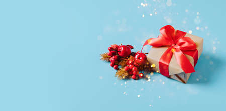 Festive box with a red bow on blue background with sparkles and candy. New Year Christmas concept....