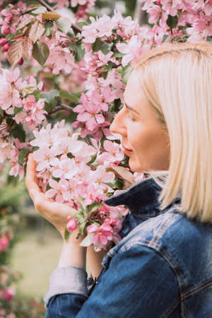 Young woman among the blossoming trees. Spring nature park or garden, flowering trees. Concept spring woman healthの写真素材