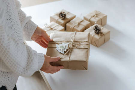 Womens hands are preparing for Christmas packing gifts. Preparing for winter holidays making...