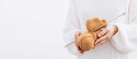 Womens hands hold natural wool threads for knitting, knitting needles. Close up, selective soft focus, light backgroundの写真素材