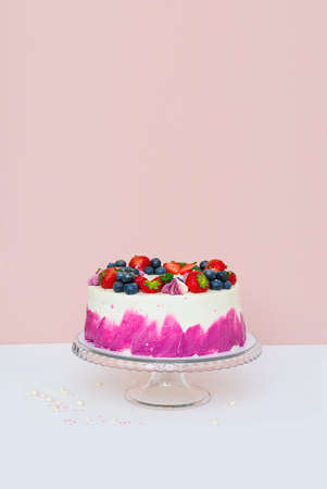 Delicate cake decorated with fresh berries, strawberries and blueberries on a light plain background