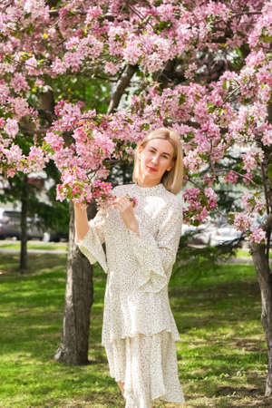 Young woman among the blossoming trees. Spring nature park or garden, flowering trees. Concept...