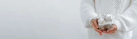 Female hands are holding small gift box. Winter holidays concept New Year Christmas. Selective focus, light backgroundの写真素材