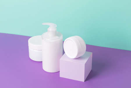 Group of cosmetics in various jars bottles of white packaging on pastel mint purple background, modern abstract podium. Copy spaceの写真素材