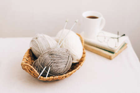 Natural wool in balls of various pastel colors in a wicker basket. Knitting threads close-up on a light background.の写真素材