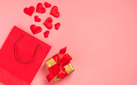 Red paper bag, red hearts and gift satin ribbon bow pink background. Festive background valentines dayの写真素材