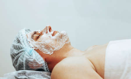 A young man lies with a mask on his face in a spa beauty salon. The concept of body and face care for menの写真素材